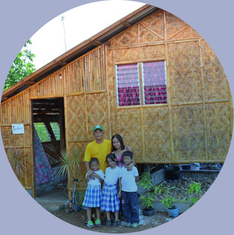 Rodzina przed domem wykonanym lokalną techniką ściany wyplatane z bambusa odbudowa po tajfunie Bantayan, Filipiny, 2014.