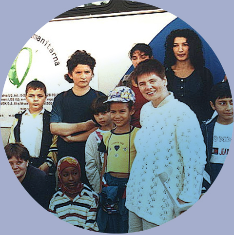 Janka Ochojska wśród dzieci cudzoziemskich jadących na wakacje zorganizowane przez Polską Akcję Humanitarną, 2000 rok. Fot.: PAH