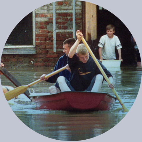 Powodzianie w łódce i pontonie przed zalanym domem, Polska 2001 rok. Fot.: PAH